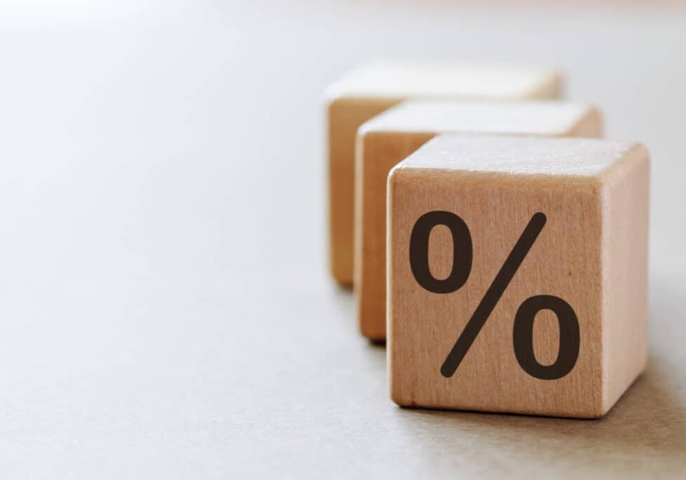 A wooden dices with percent symbol on one side, sitting on light grey background with copy space. Finance or statistics concept